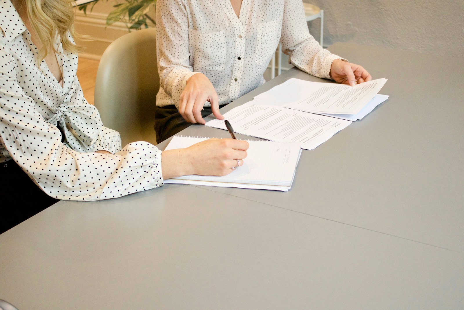 Zwei Frauen besprechen und unterschreiben Unterlagen an einem Tisch
