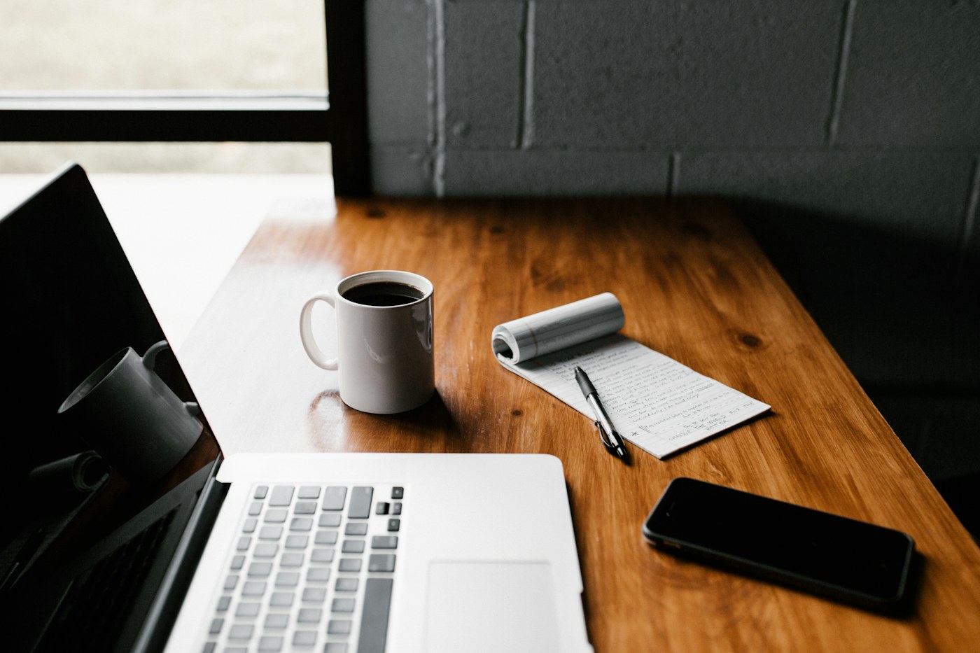 Schreibtisch mit Laptop, Notizbuch und Smartphone