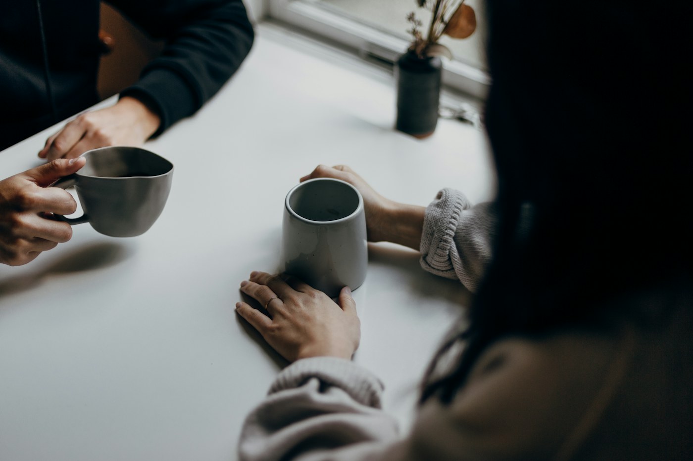 Zwei Menschen sitzen mit Kaffeetassen an einem Tisch